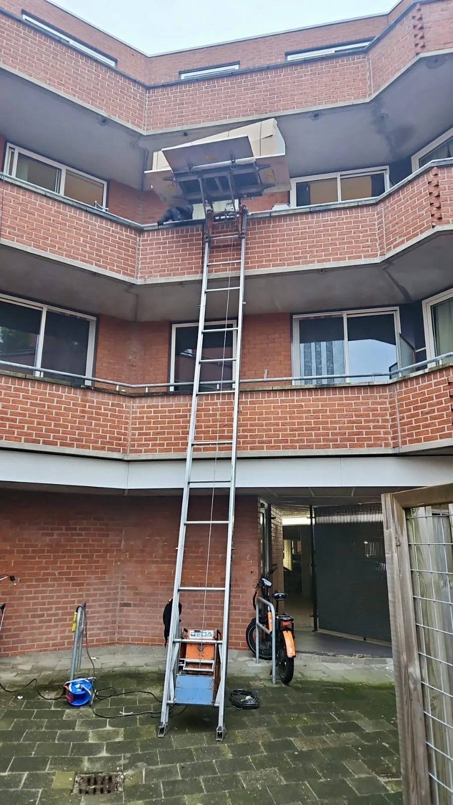 Opbouwlift op de binnenplaats van een flat hijst meubels omhoog