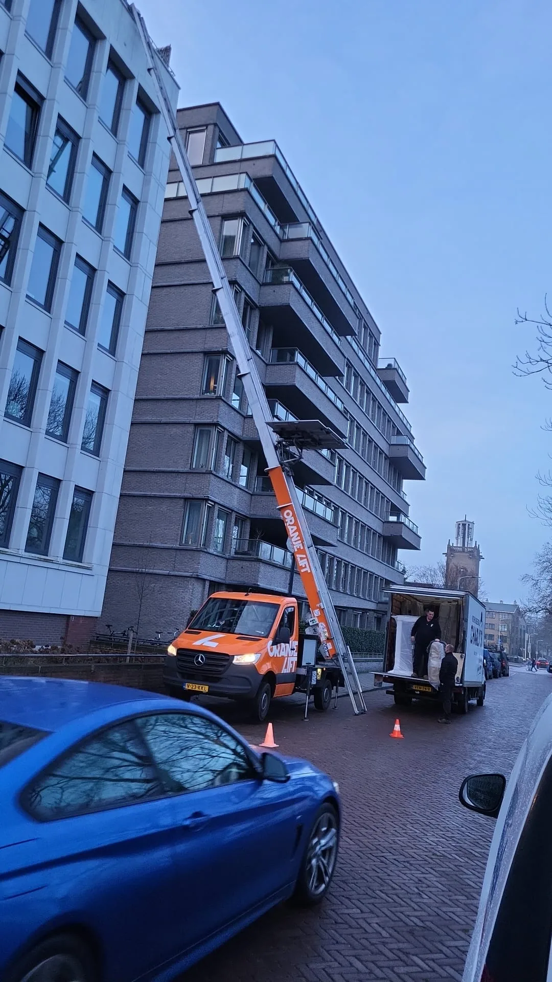 Verhuislift langs hoog flatgebouw met uitgeschoven ladder