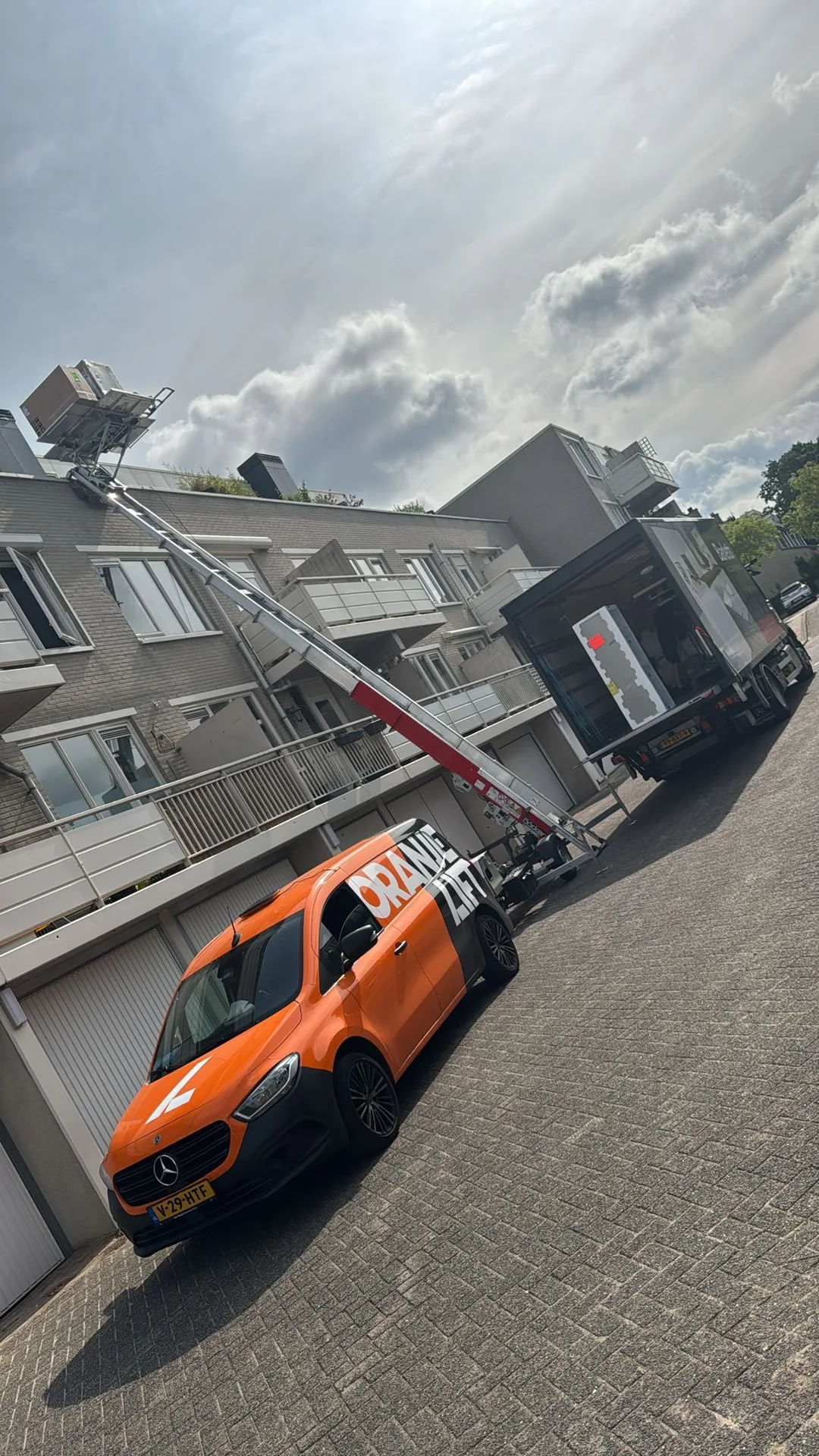 Verhuislift naast een verhuiswagen terwijl meubels worden ingeladen